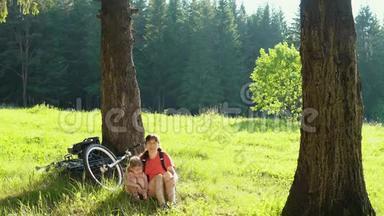 这家人在阳光明媚的日子里骑自行车在夏天的森林里休息。